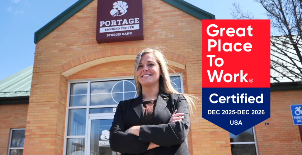 Confident smiling woman standing with arms crossed in front of a Sturgis Bank branch.